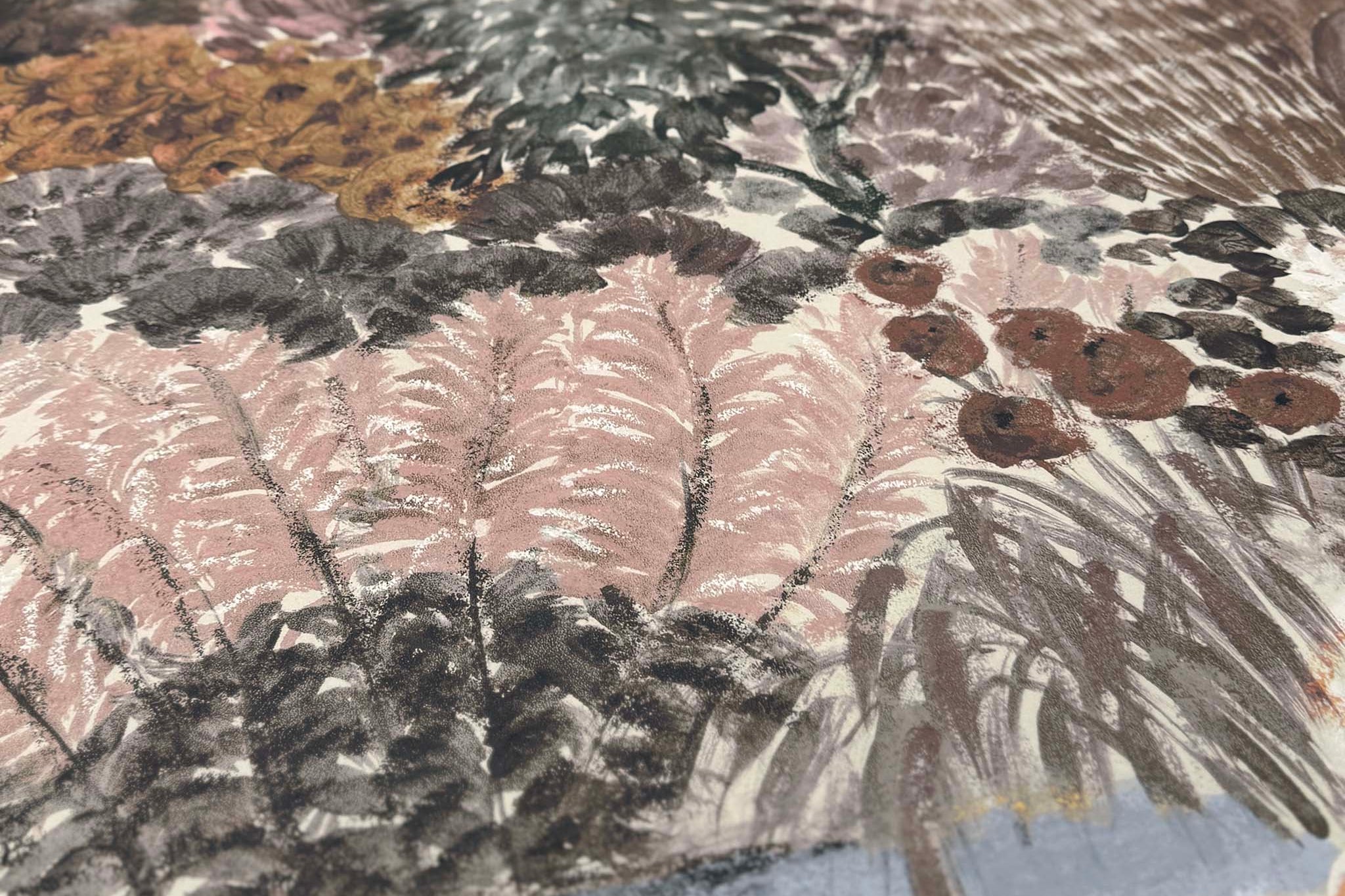 A close up view showing the detail of a matte wallpaper mural which features warm clays, soft plum, and rusted greens