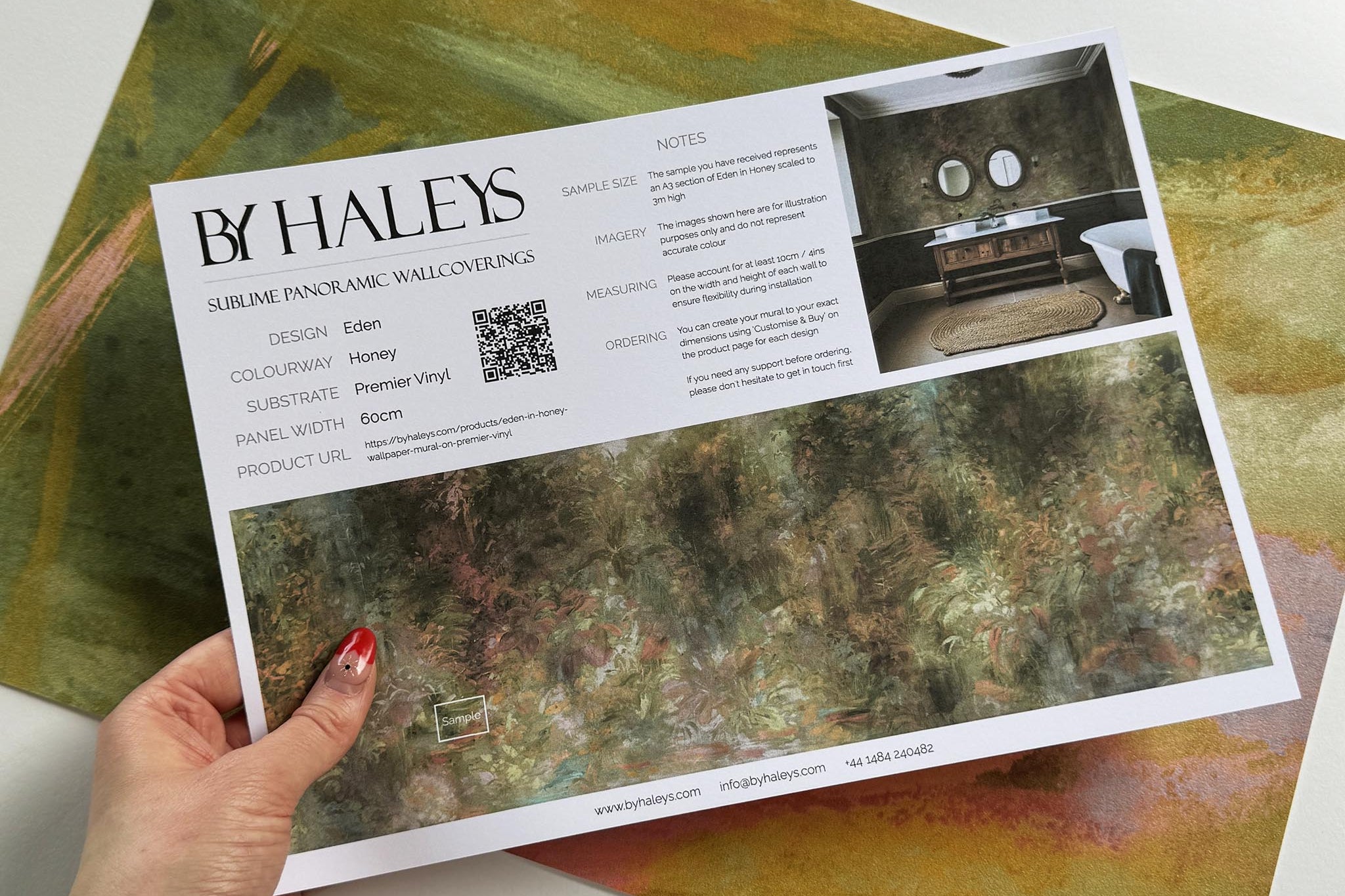 A hand showing information for a vinyl wallpaper mural sample which features a abstract layering of ochre and teal.