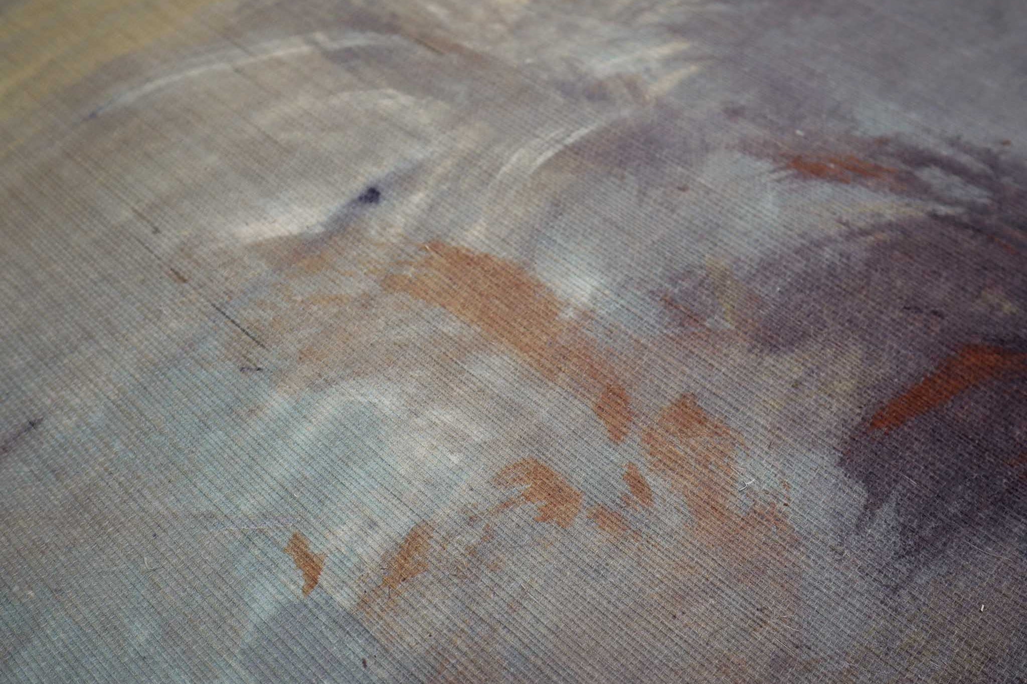 Close-up of a textured grasscloth wallpaper mural in rich shades of charcoal, rust, and ochre, featuring abstract design.