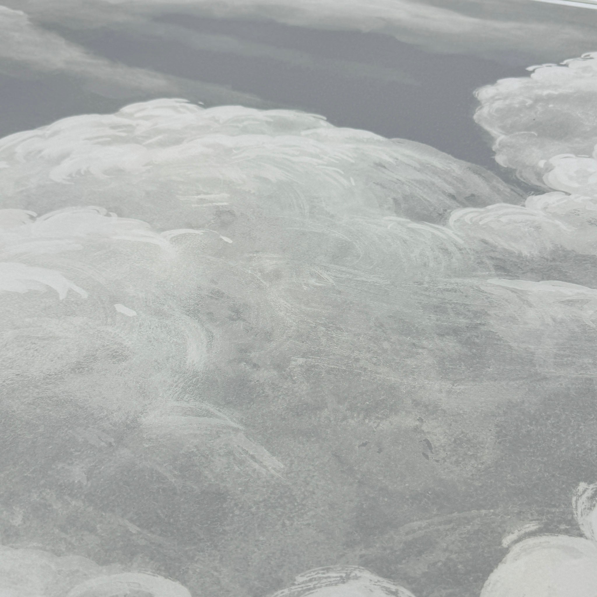 A close up view showing the detail of a matte wallpaper mural which features pale sculpted clouds