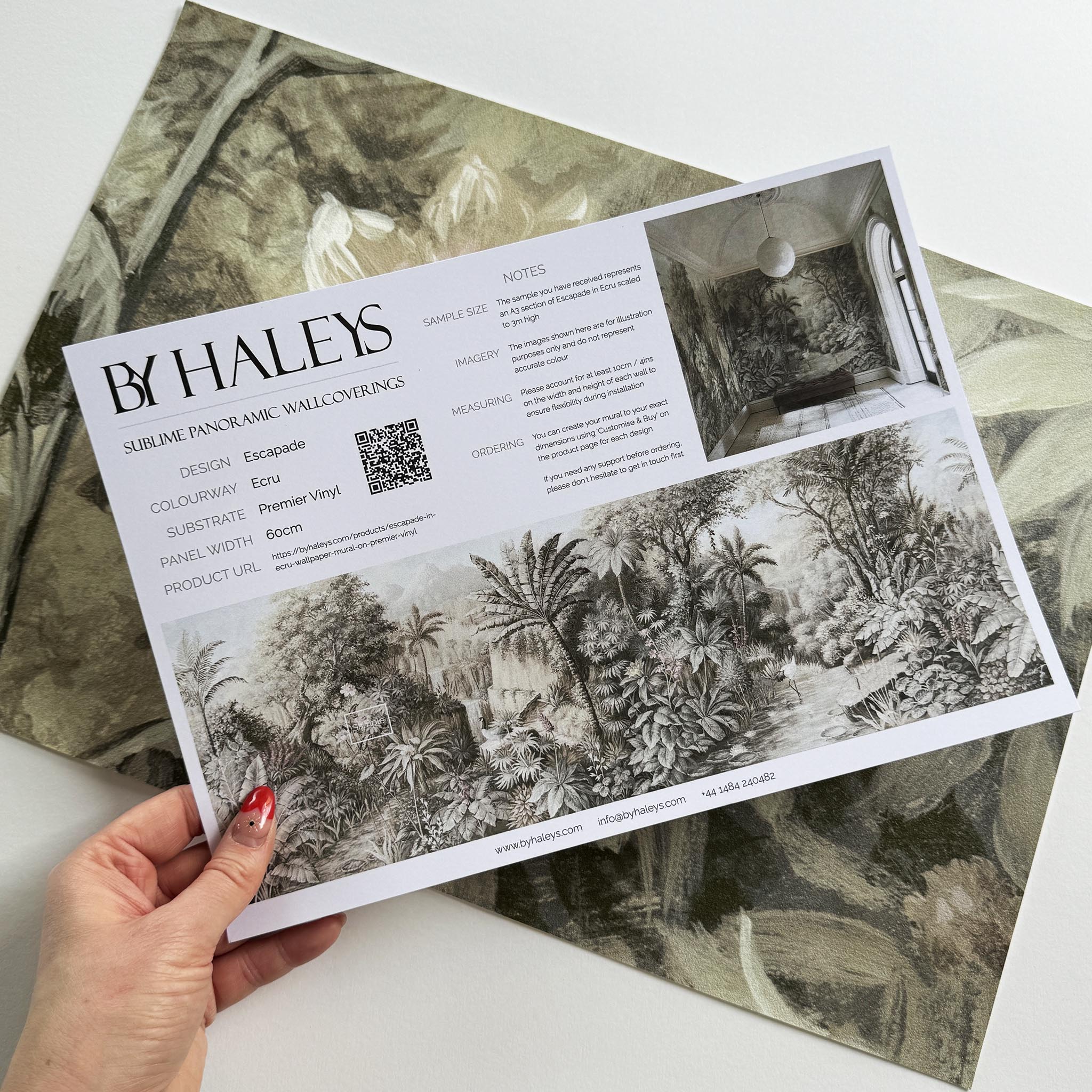 A hand showing information for a vinyl wallpaper mural sample which features a jungle vista in sepia and blush.