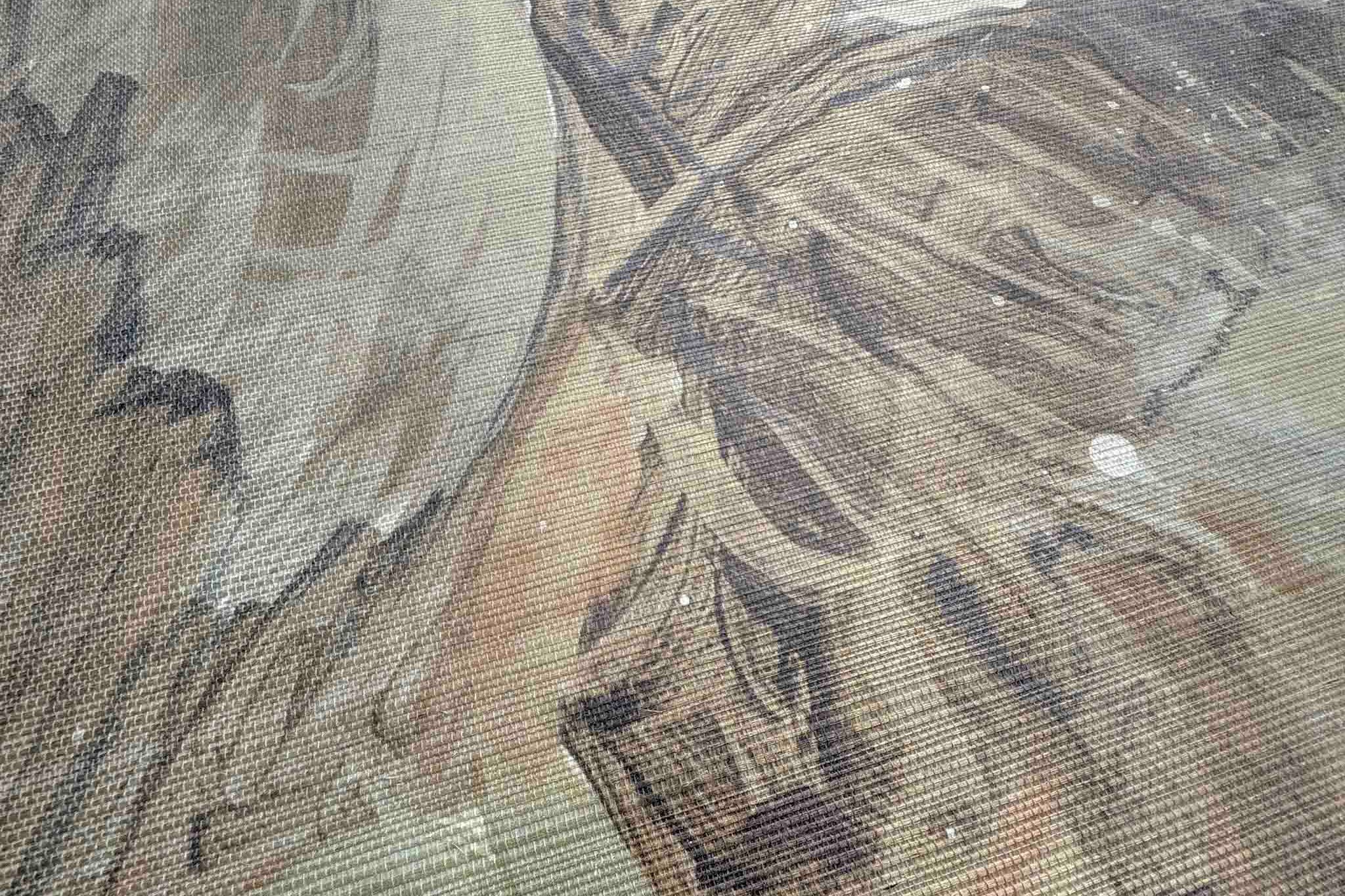 Close-up of a wallpaper mural with soft sandy hues and muted greens, featuring abstract tropical foliage on grasscloth.