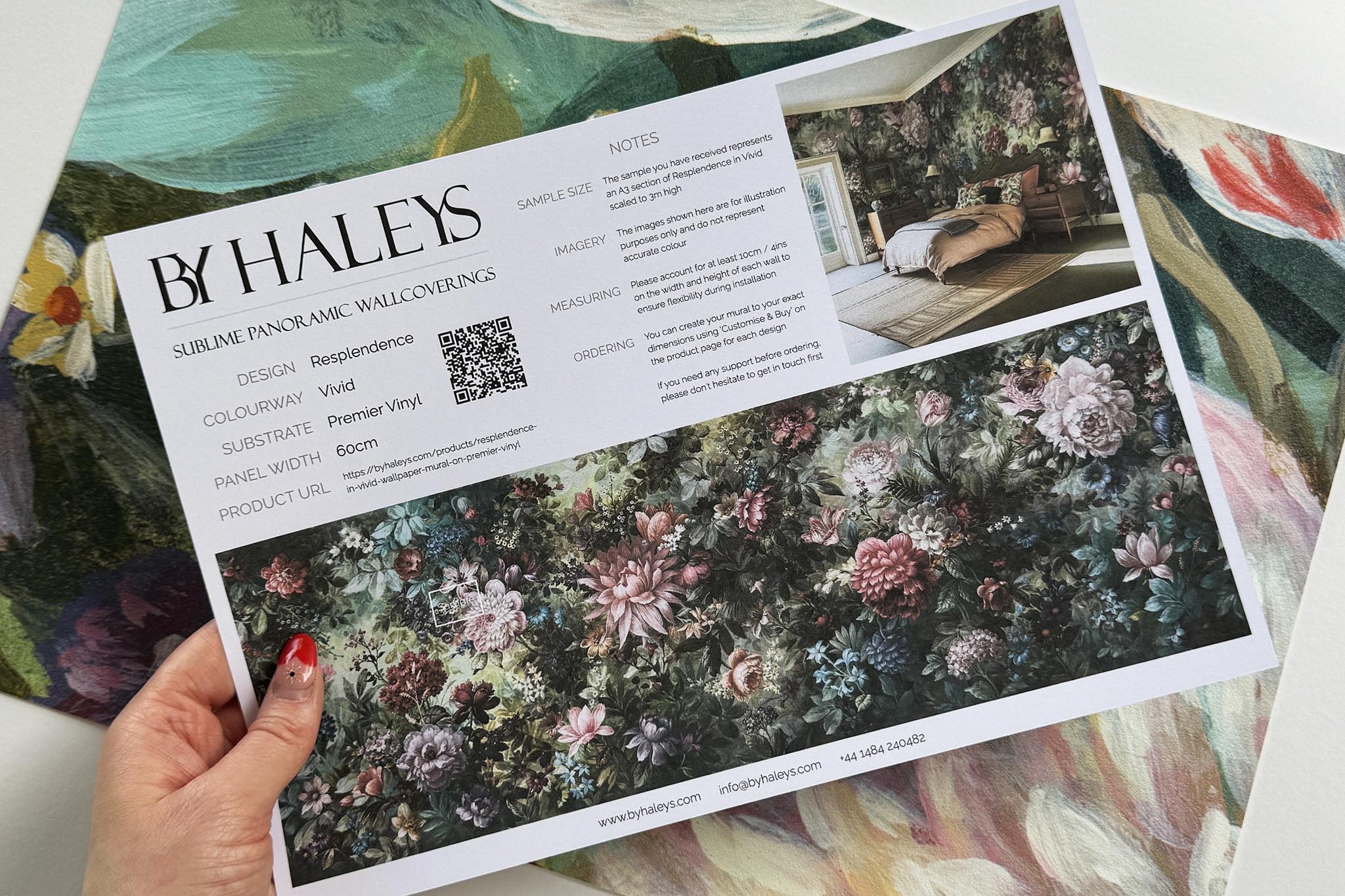 A hand showing information for a vinyl wallpaper mural sample which features a floral tapestry in rich jewel tones.