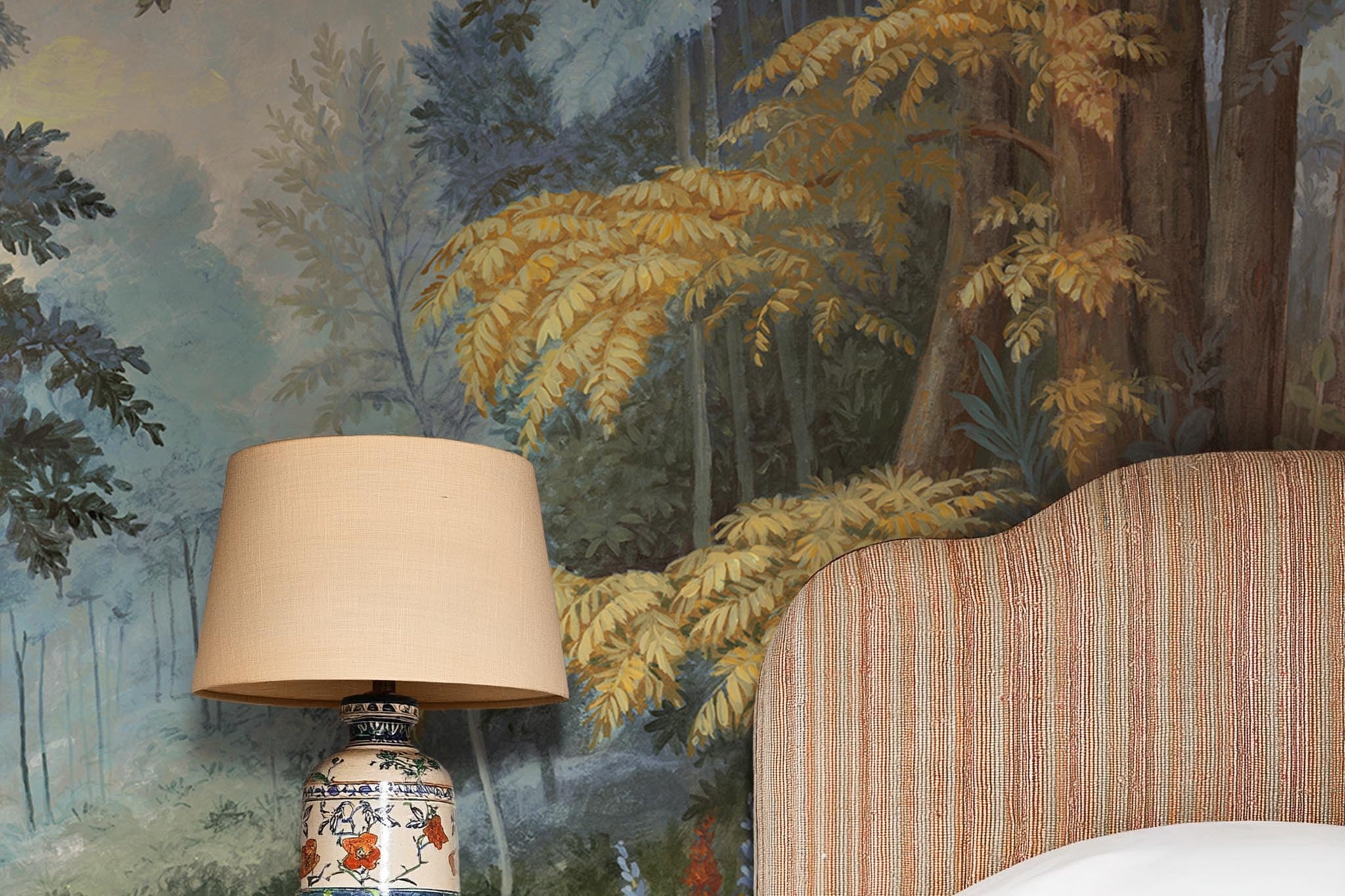 A cropped view of bedroom featuring a panoramic matte wallpaper mural of an enchanted forest in blue and rust.