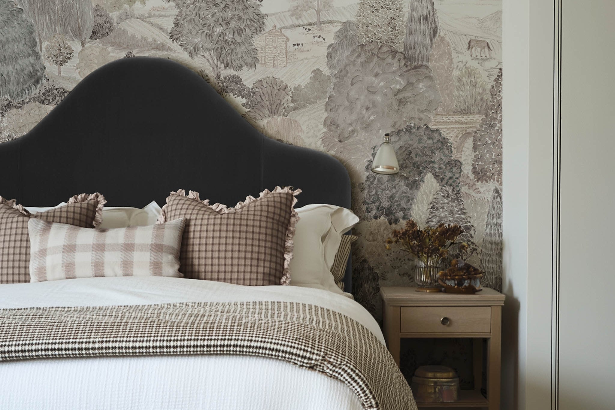 A cropped view of a bedroom featuring a panoramic matte wallpaper mural of almond, dusty rose, and mist countryside scene