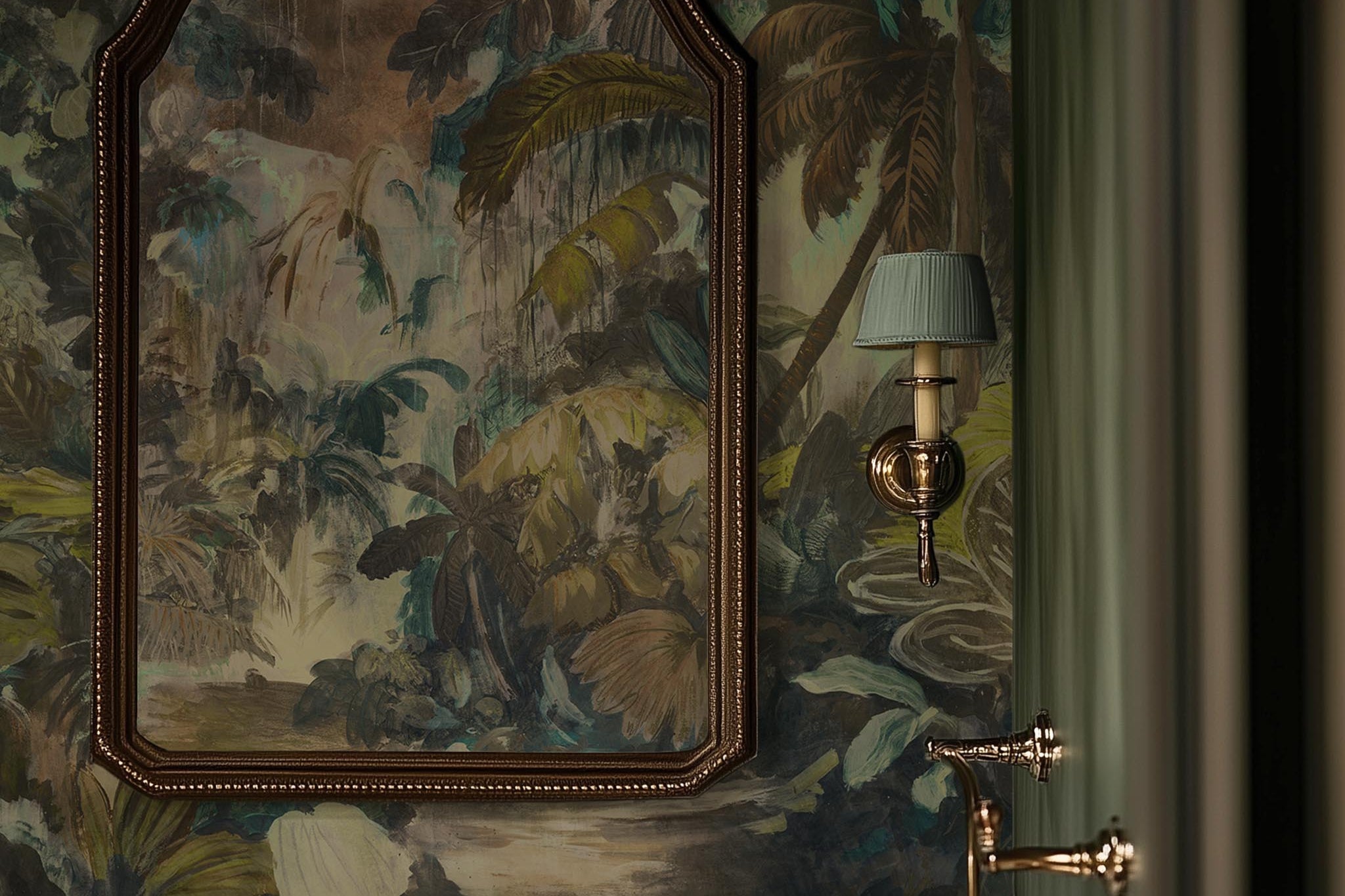 A cropped view of bathroom featuring a panoramic vinyl wallpaper mural of a moody jungle in teal and ochre.