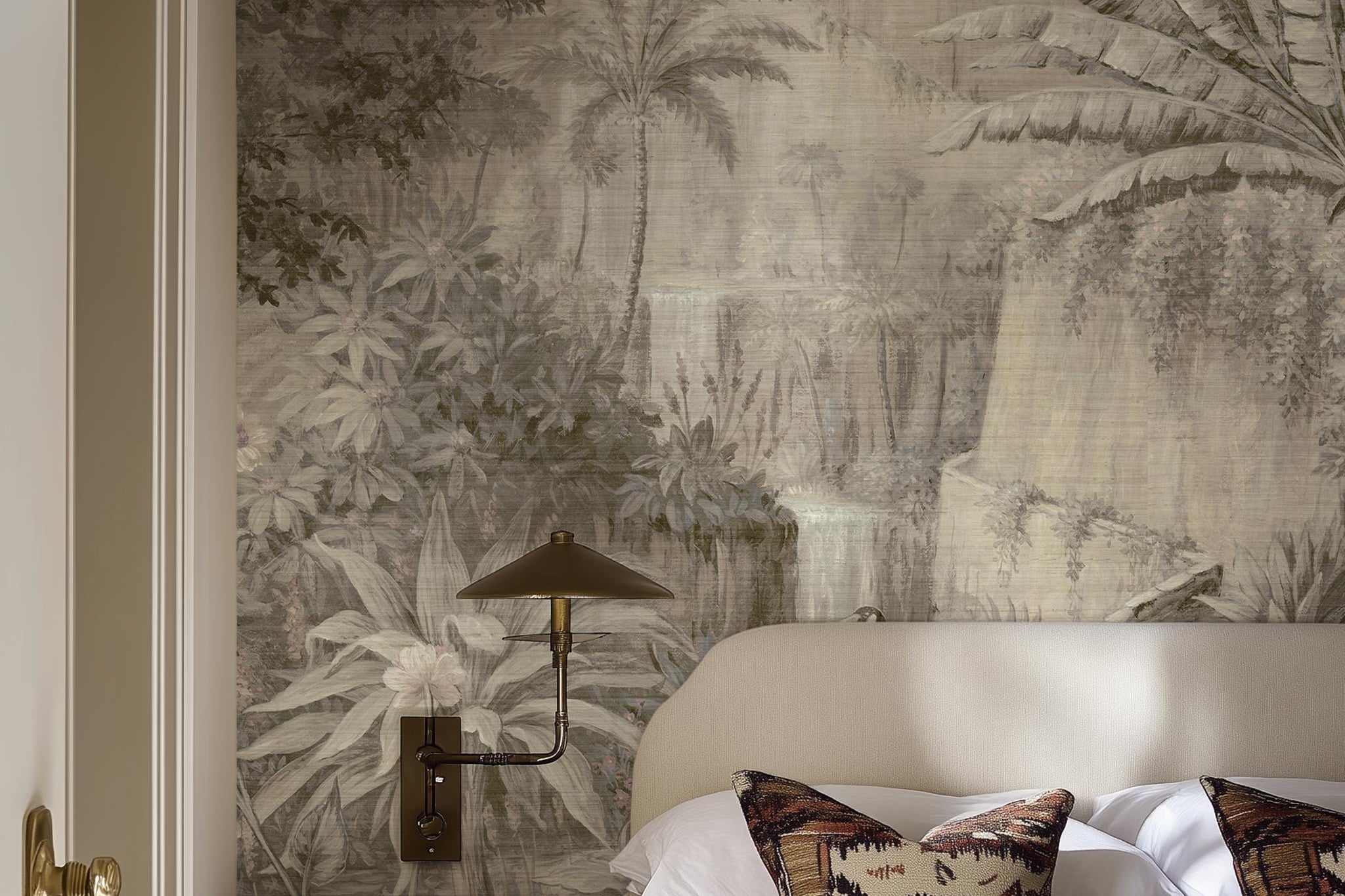A cropped view of bedroom featuring a panoramic grasscloth wallpaper mural of a jungle vista in sepia and blush.