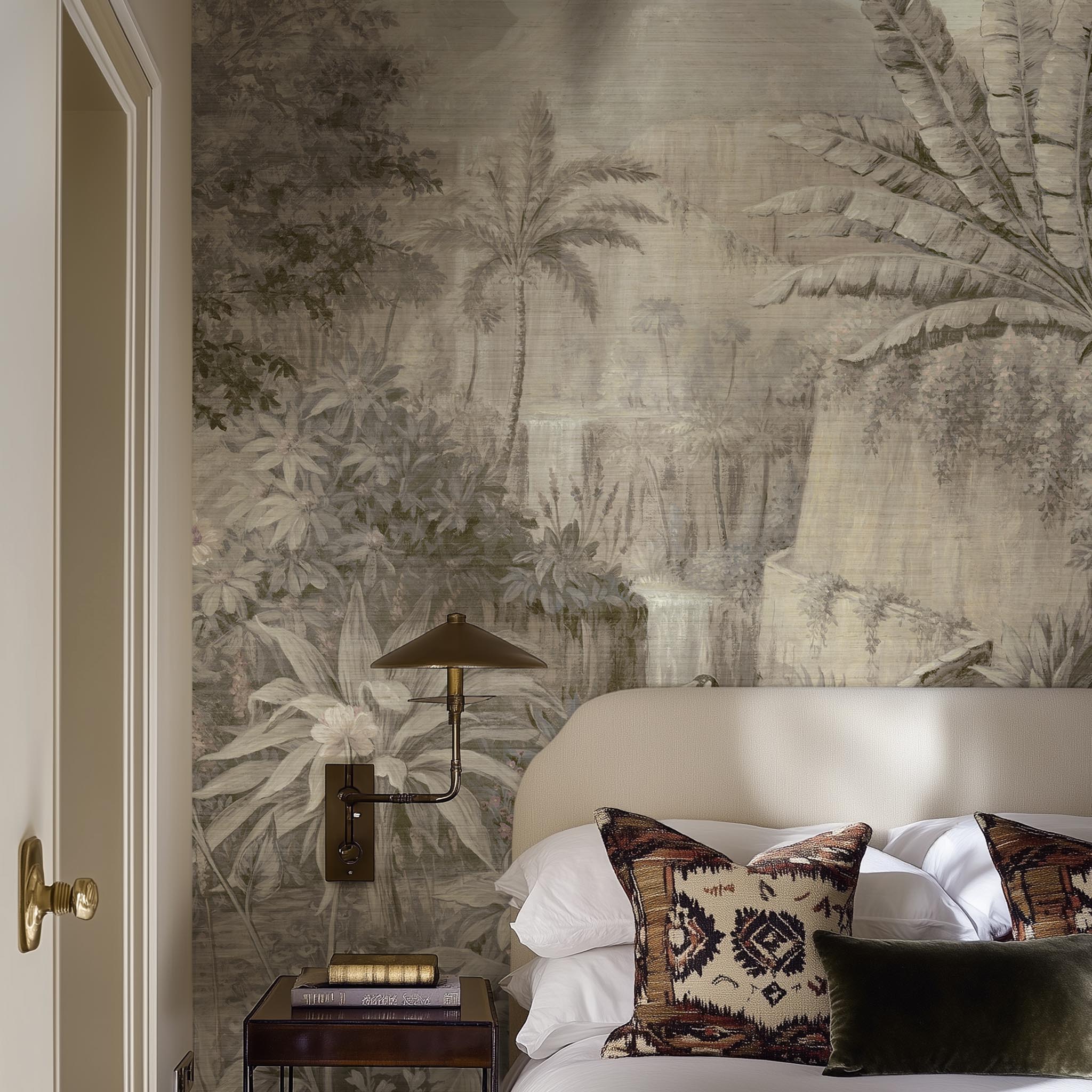 A cropped view of bedroom featuring a panoramic grasscloth wallpaper mural of a jungle vista in sepia and blush.