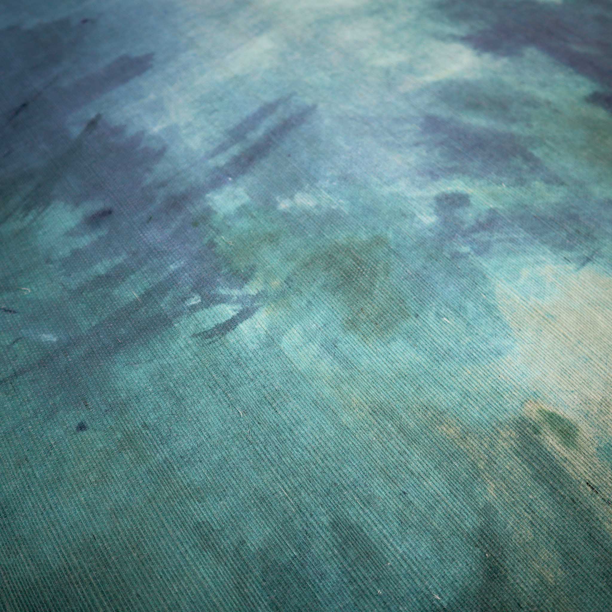 Close-up of a textured grasscloth wallpaper mural featuring fluid aqua and teal tones and painterly brush strokes.