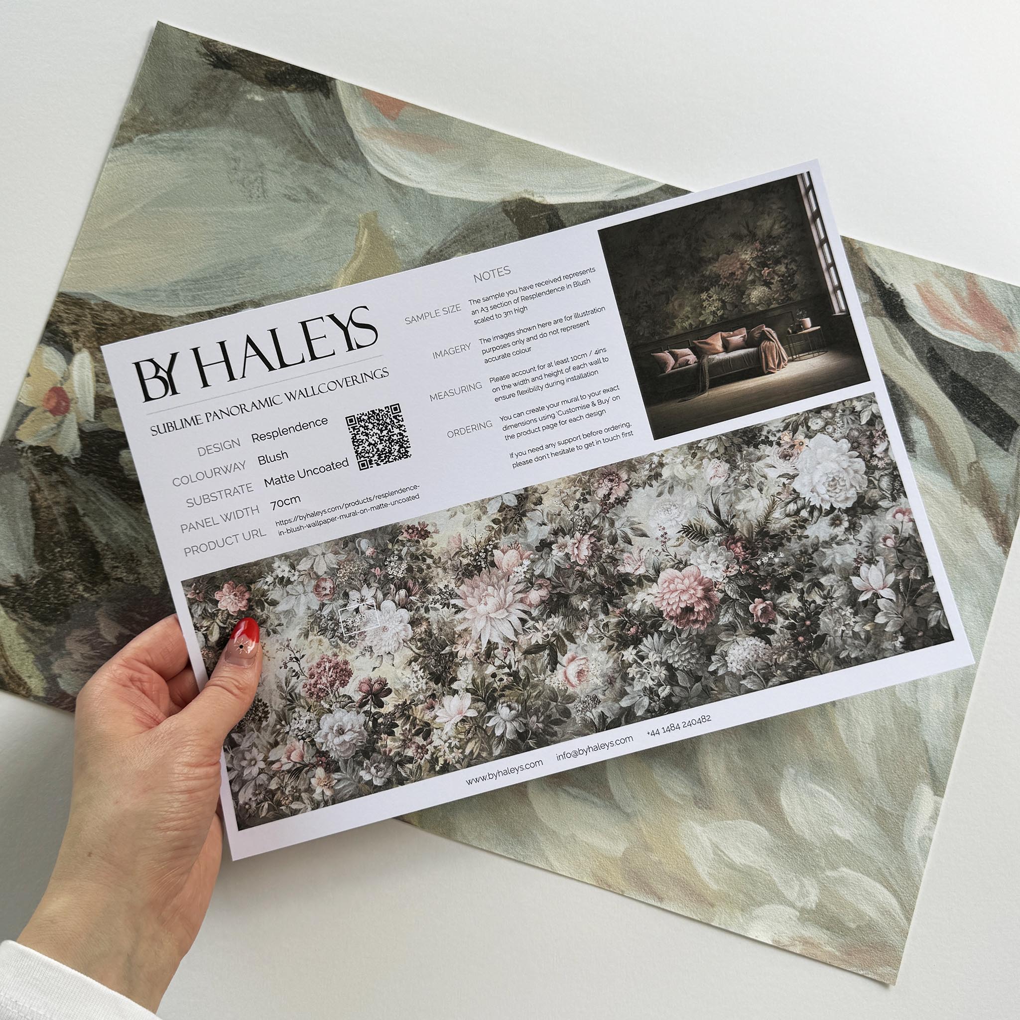 A hand showing information for a vinyl wallpaper mural sample which features a floral composition in soft neutrals.