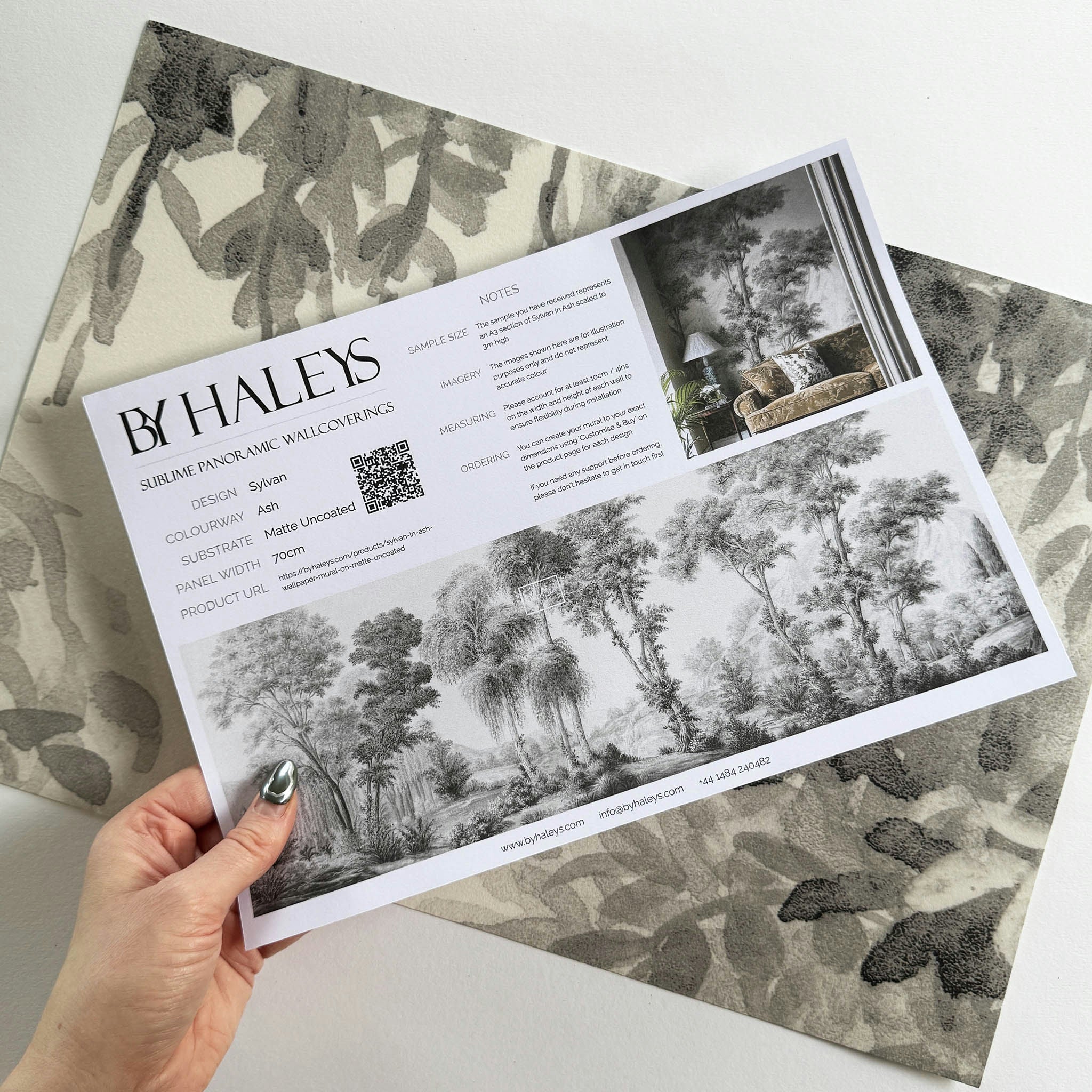 A hand showing information for a matte wallpaper mural sample which features ash grey forest