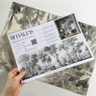 A hand showing information for a matte wallpaper mural sample which features ash grey forest