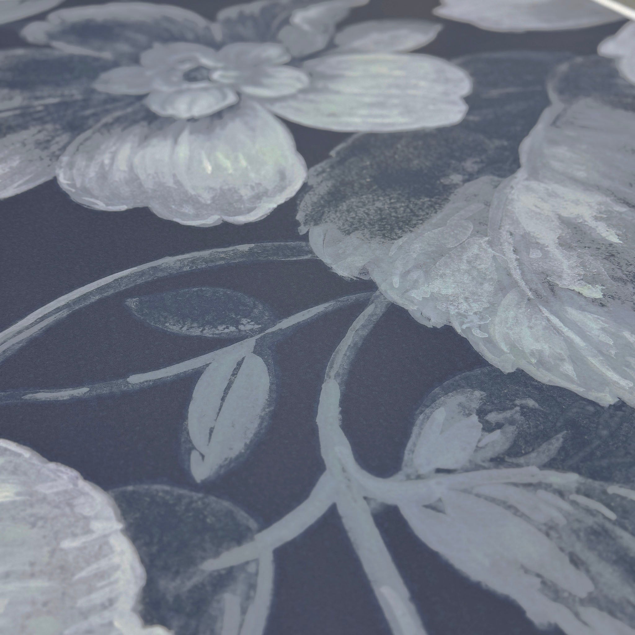 A close up view showing the detail of a matte wallpaper mural which features moonlit florals on deep navy