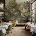 An interior restaurant featuring a panoramic grasscloth wallpaper mural of a tropical scene in green and pink.