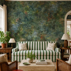 A cropped view of a living room featuring a panoramic pearlescent wallpaper mural of moody nettle-green mural with sage, charcoal and rust colours.
