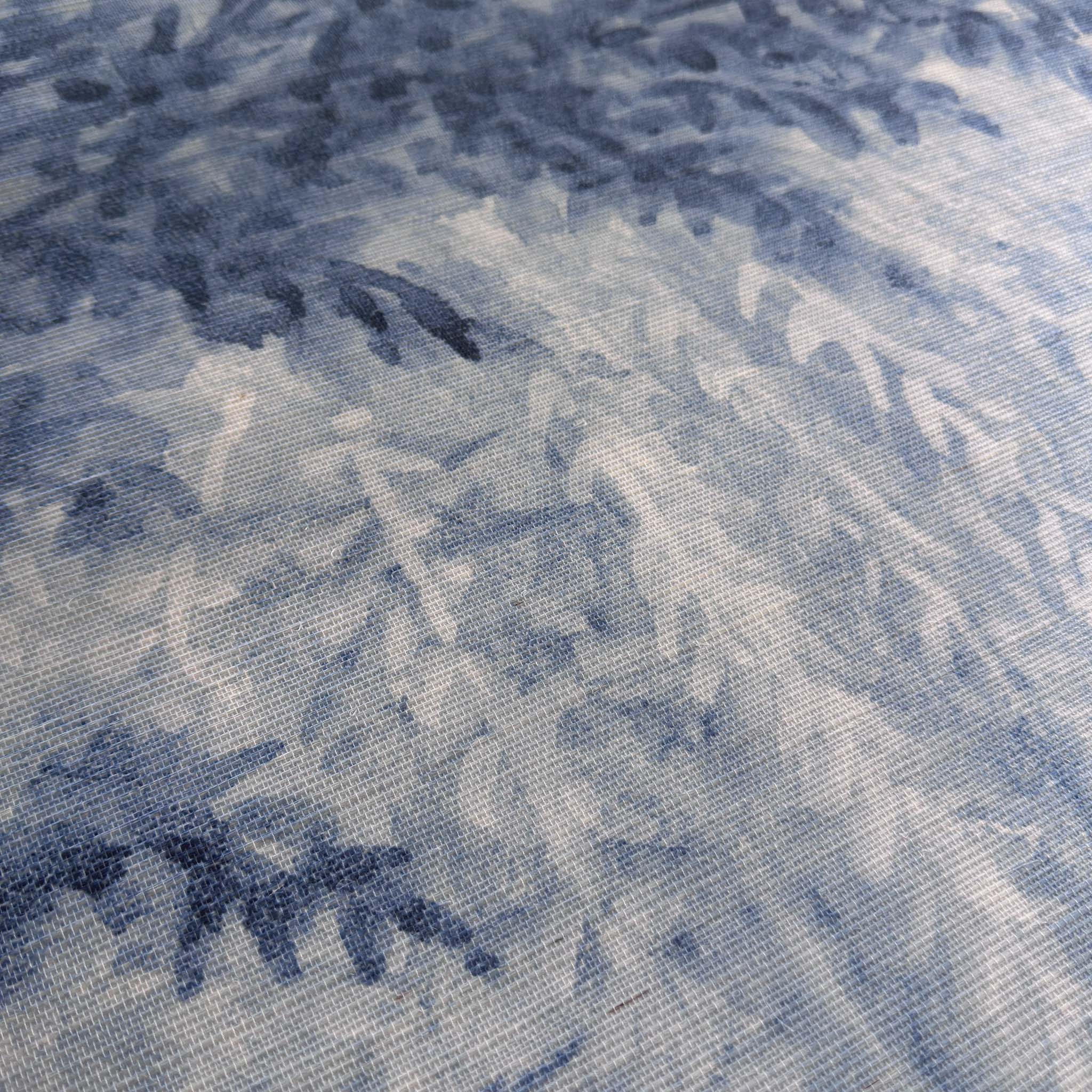 A close up view showing the detail of a grasscloth wallpaper mural which features soft blue woodland