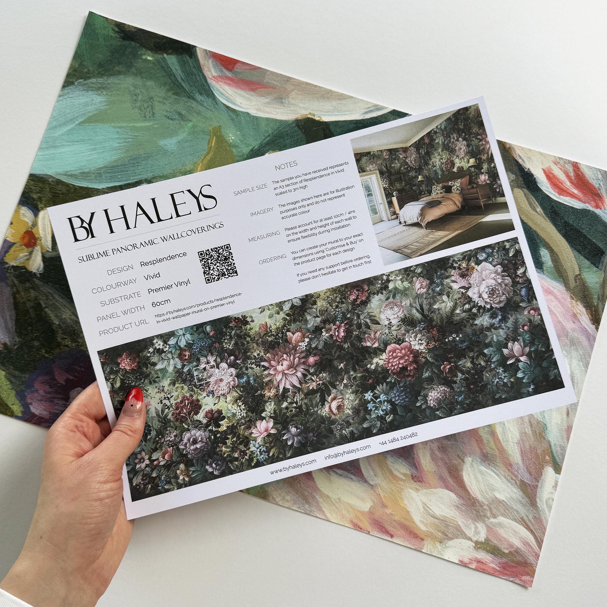 A hand showing information for a vinyl wallpaper mural sample which features a floral tapestry in rich jewel tones.