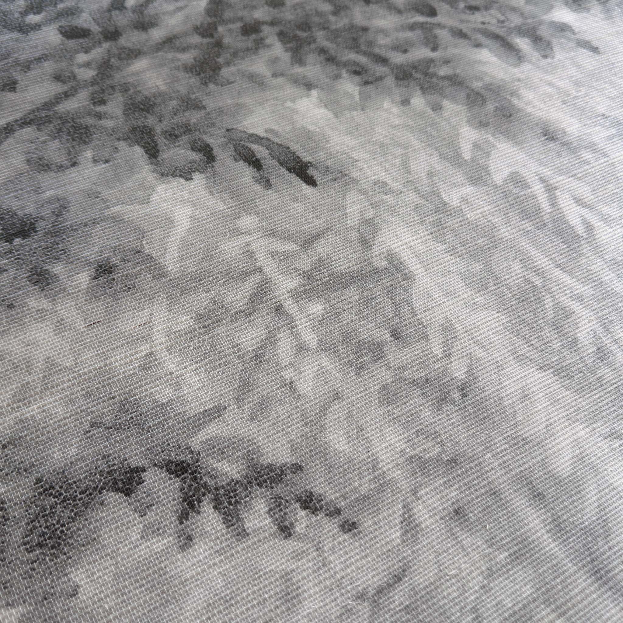 A close up view showing the detail of a grasscloth wallpaper mural which features ash grey forest