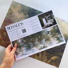 A hand showing information for a pearlescent wallpaper mural sample which features softly shaded panoramic green mural.