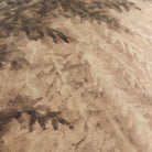 A close up view showing the detail of a grasscloth wallpaper mural which features sepia-toned woodland