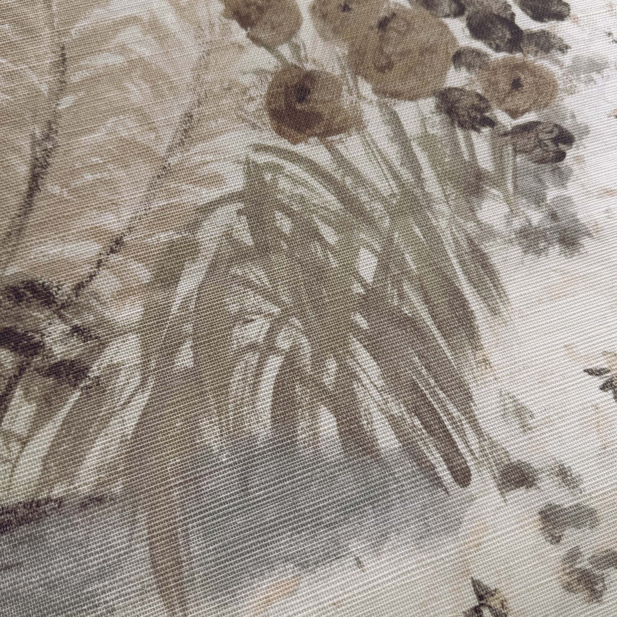 A close up view showing the detail of a grasscloth wallpaper mural which features a countryside in almond, dusty rose, and mist