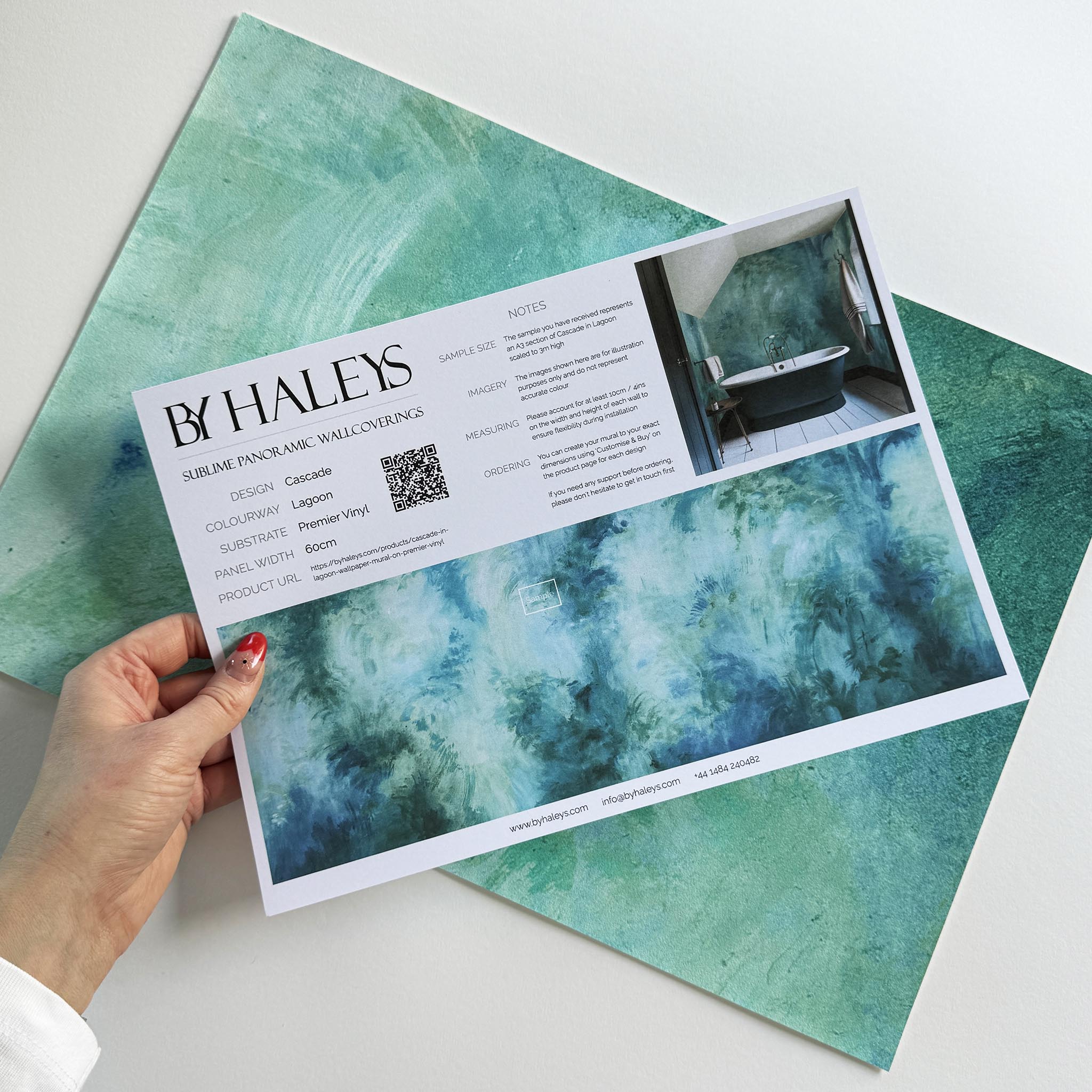 A hand showing information for a vinyl wallpaper mural sample which features an abstract wash in aqua and jade.