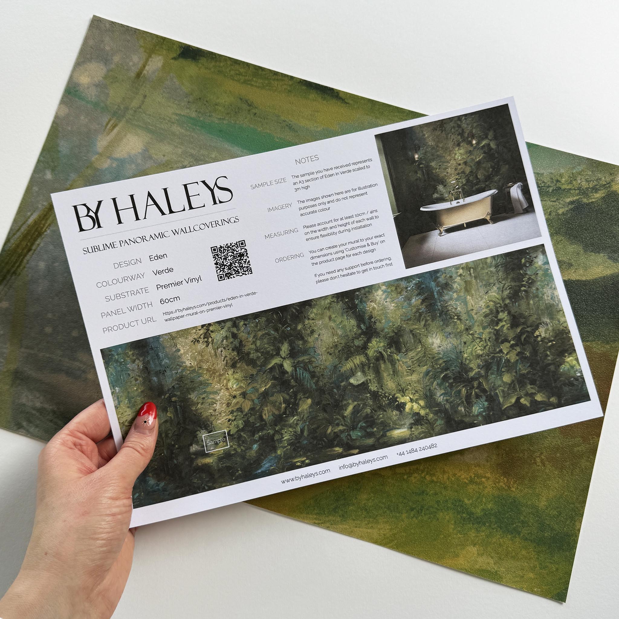A hand showing information for a vinyl wallpaper mural sample which features a jungle abstraction in emerald and ochre.