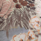 A close up view showing the detail of a grasscloth wallpaper mural which features a countryside in clay and soft plum tones