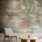 A cropped view of a sitting area featuring a panoramic pearlescent wallpaper mural of soft mural in chicory blue, dusty rose, sage and ochre.