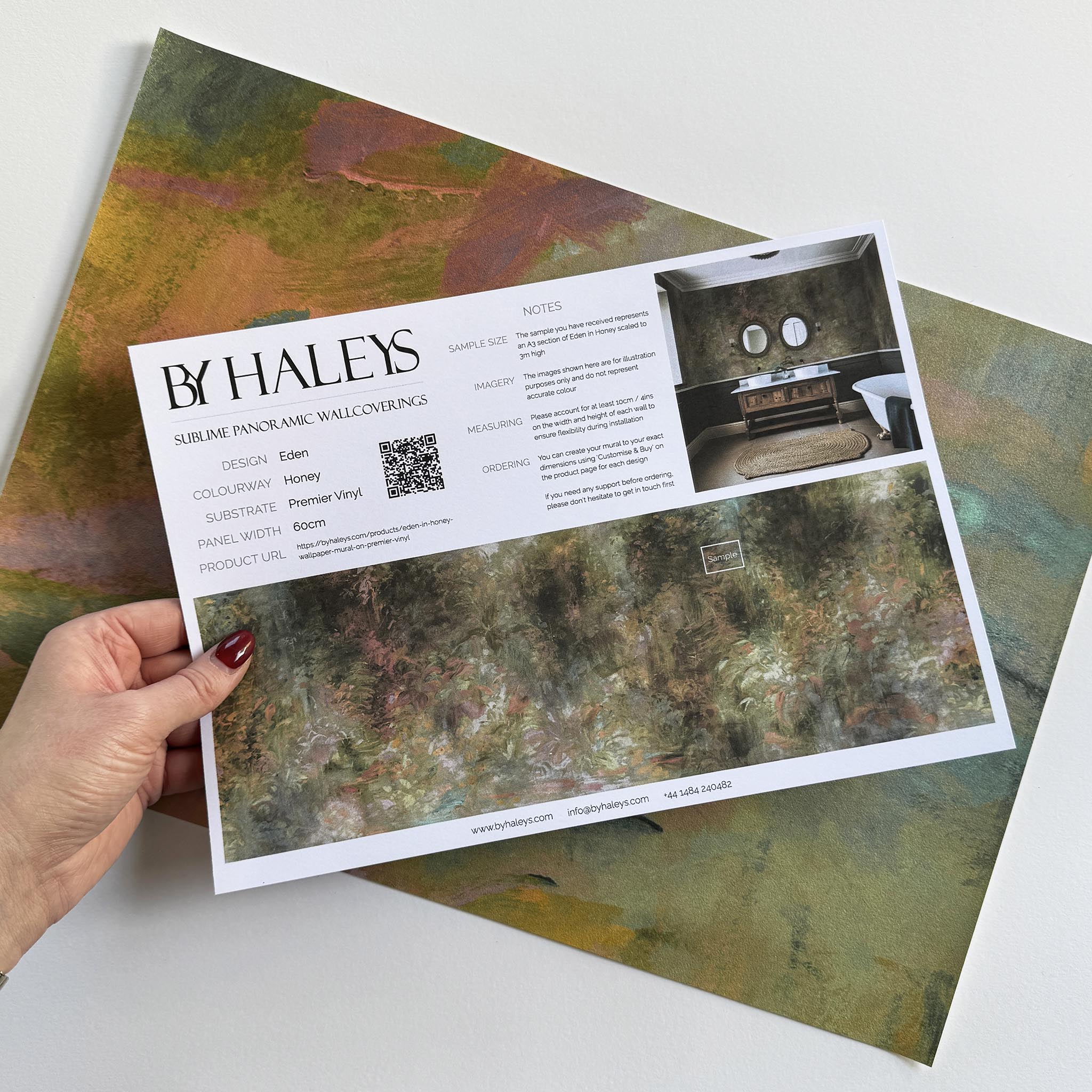 A hand showing information for a vinyl wallpaper mural sample which features a abstract layering of ochre and teal.