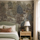 A cropped view of a bedroom featuring a panoramic grasscloth wallpaper mural of a countryside in deep olive, slate and ash