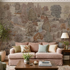 An interior living room featuring a panoramic grasscloth wallpaper mural of a countryside in clay and soft plum tones