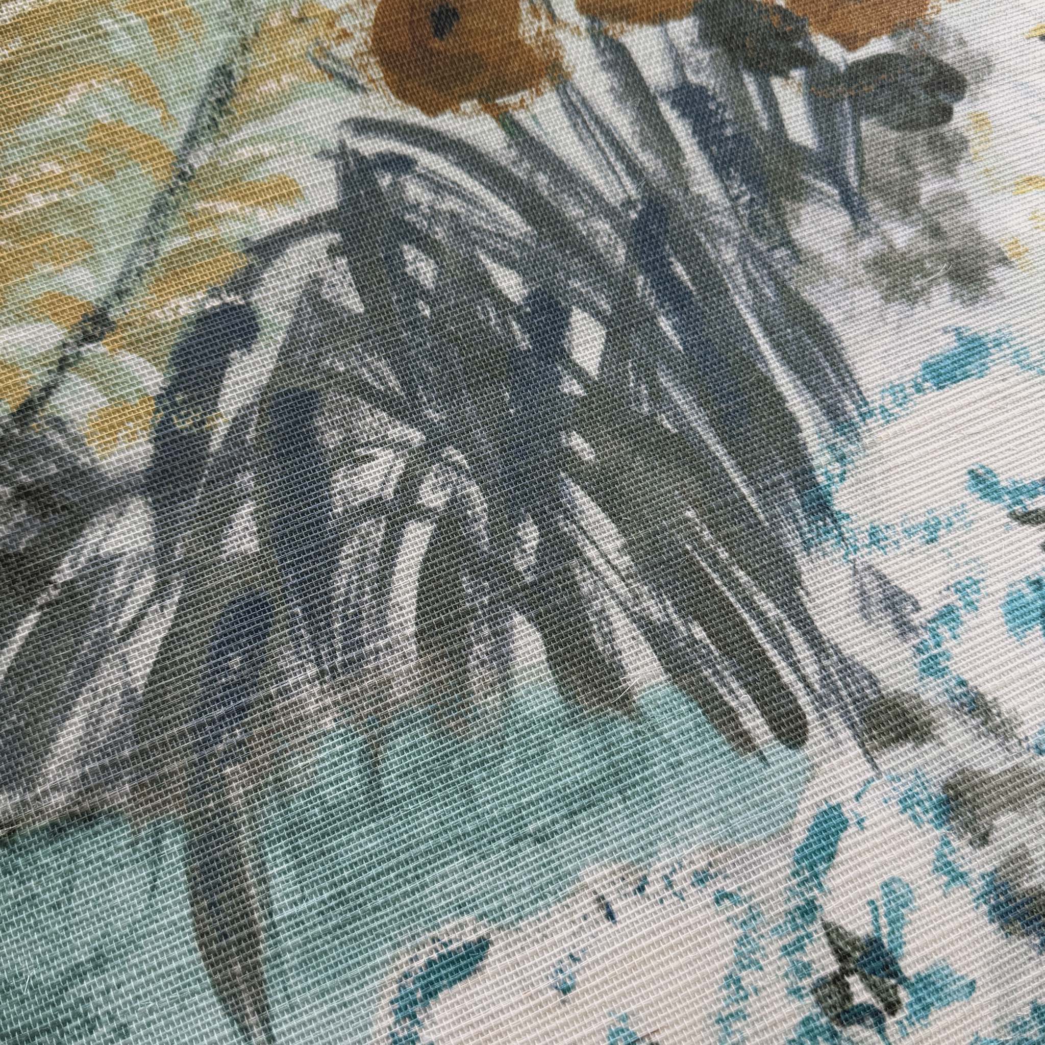 A close up view showing the detail of a grasscloth wallpaper mural which features a countryside in teal, sea green and slate