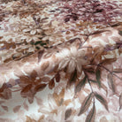 A close up view showing the detail of a pearlescent wallpaper mural which features saffron and dusky-rose mural with soft foliage.